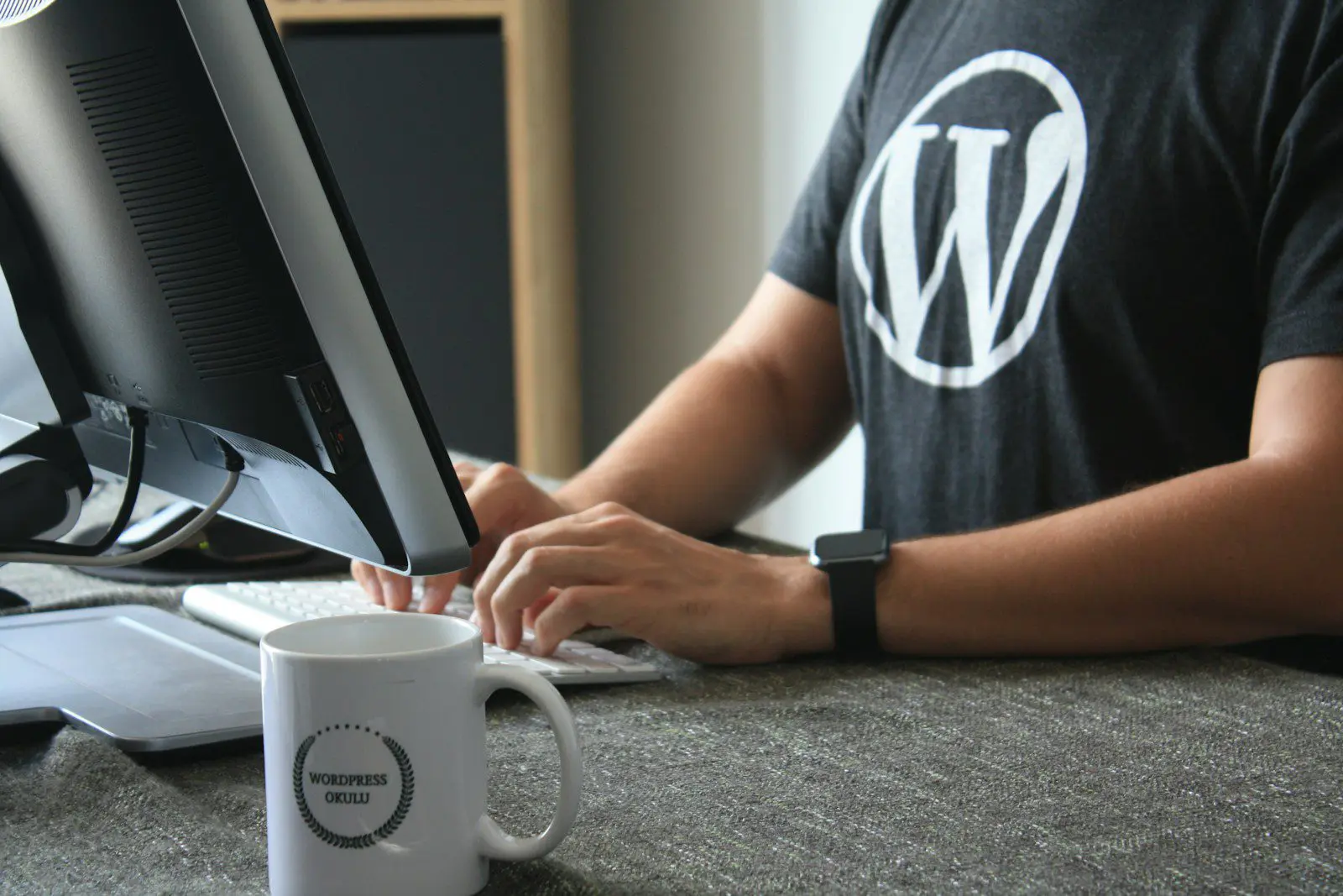 person in black and white wordpress t-shirt using computer